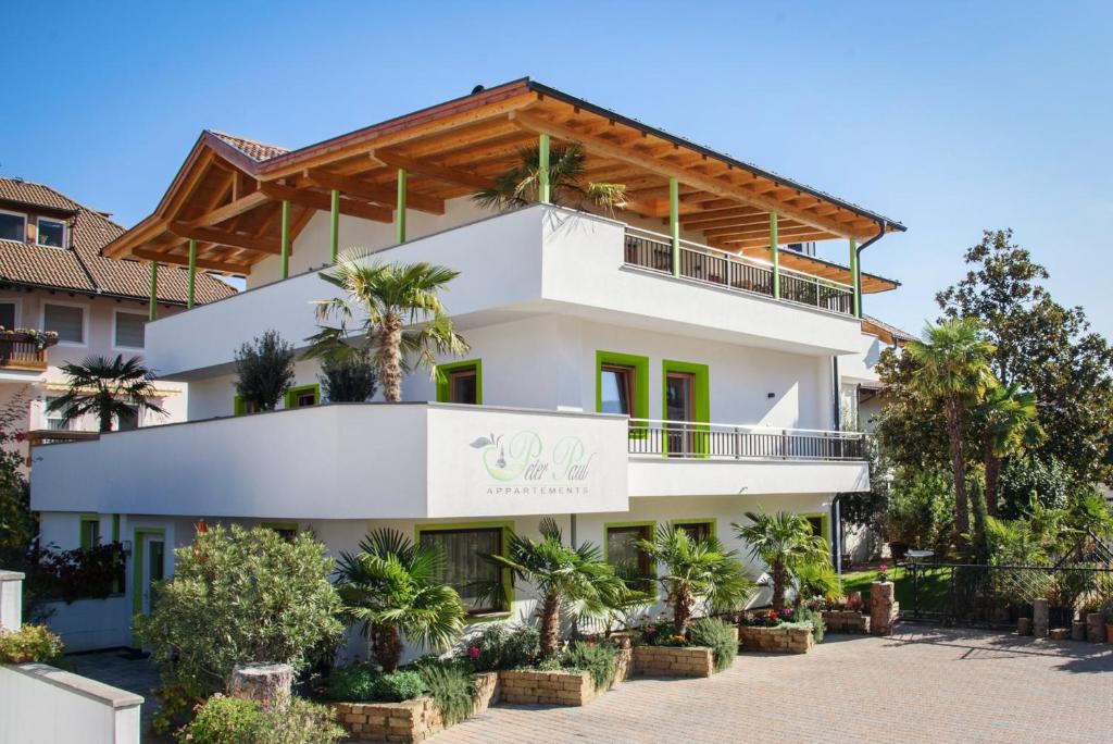 a large white building with palm trees in front of it at Peter Paul Studio Penegal in Appiano sulla Strada del Vino