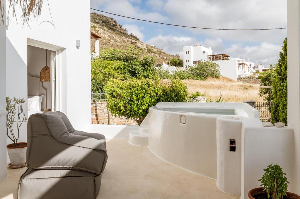 a soaking tub in a room with a view of a house at Aeolos Thalia Suite in Agkidia