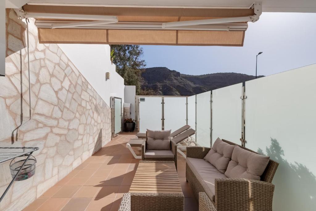 an outdoor patio with chairs and a stone wall at Vv Timón in Puerto de Mogán