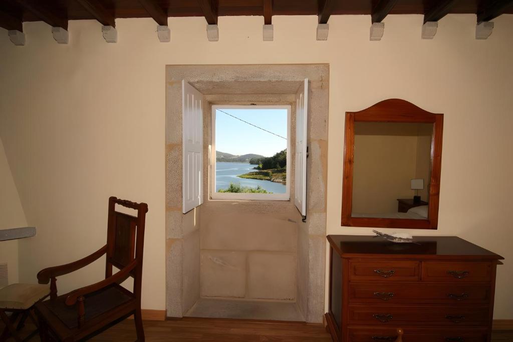 a room with a window and a dresser and a mirror at O Lar de Natalio in Rianjo