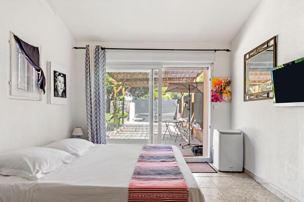 a bedroom with a bed and a door to a patio at Appartement Pinède Romane Fréjus in Fréjus