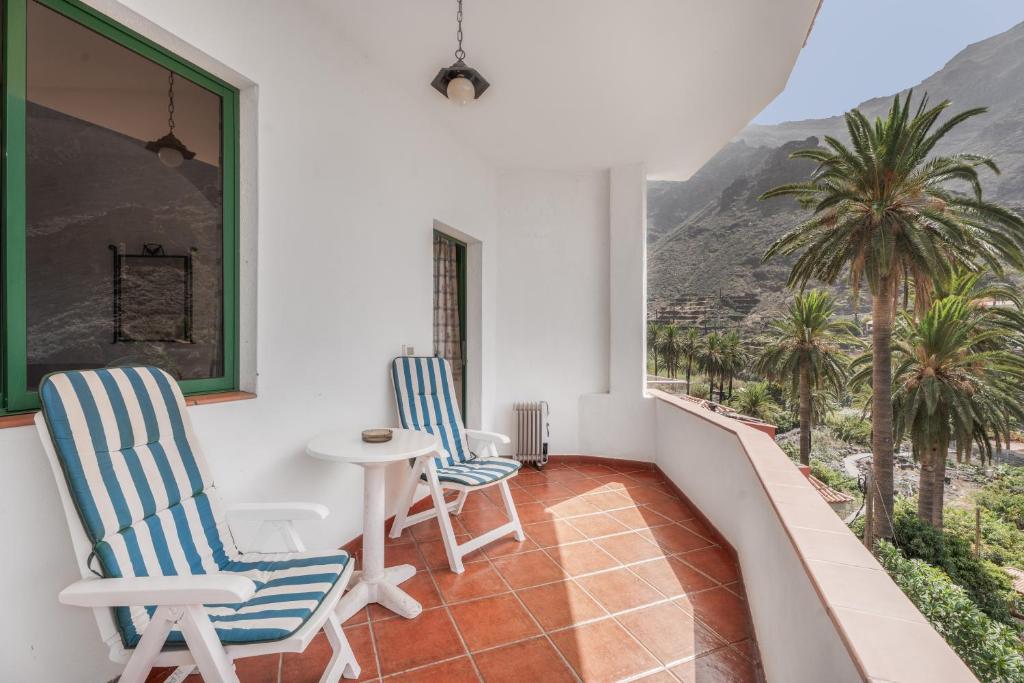 a balcony with two chairs and a table and palm trees at Apartamento Nayara B in Valle Gran Rey