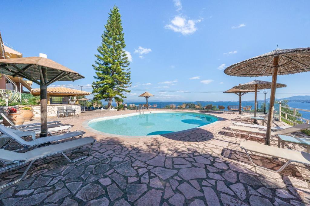 a swimming pool with chairs and umbrellas at Stefanos place Studio sea View 7 in Corfu