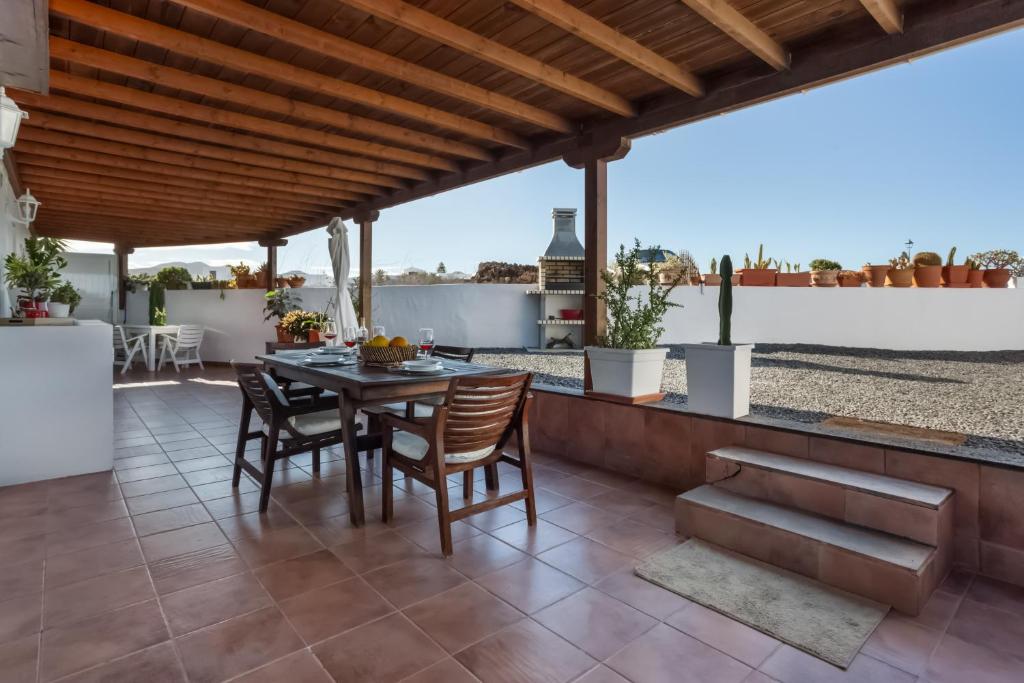 a patio with a table and chairs under a wooden roof at Almar in Tinajo