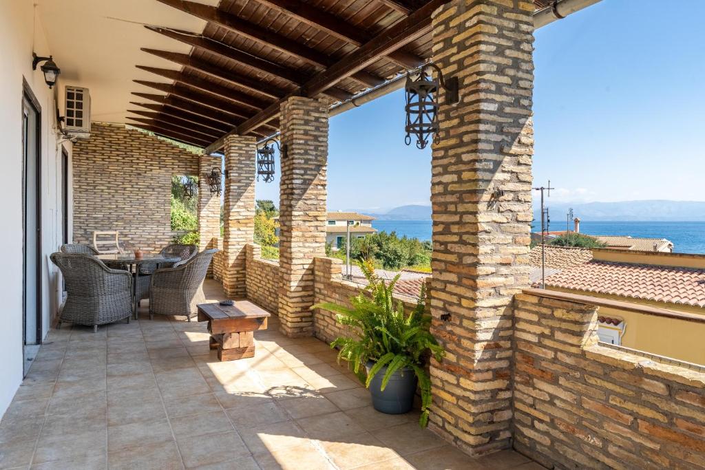 an outdoor patio with a table and a brick wall at Villa Marianthi-kaizer Bridge in Achílleion