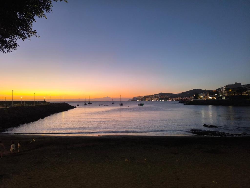 a sunset over a body of water with boats in it at Sunset Star Arguineguin in Arguineguín