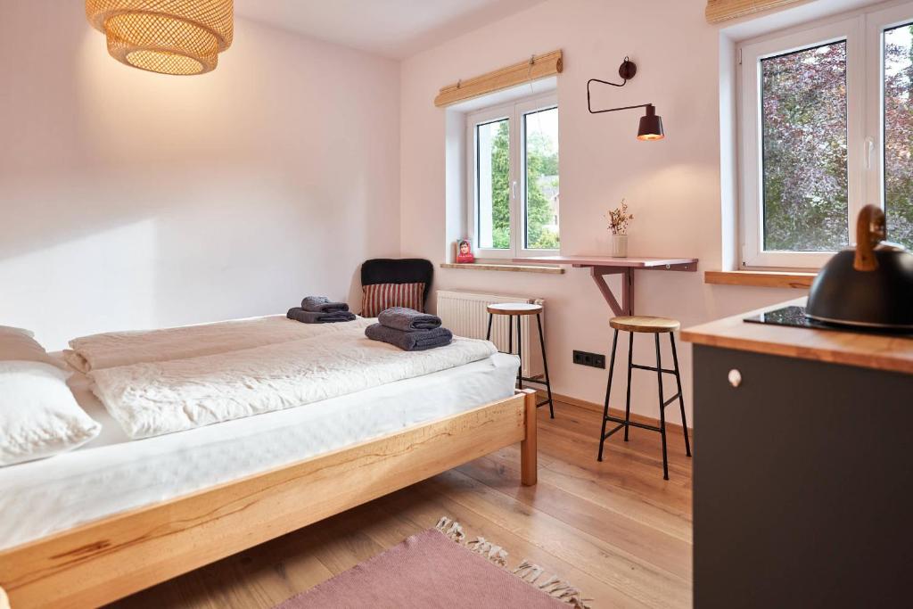 a bedroom with a bed and a table and two windows at Alte Seifensiederei - Malala in Bad Tölz
