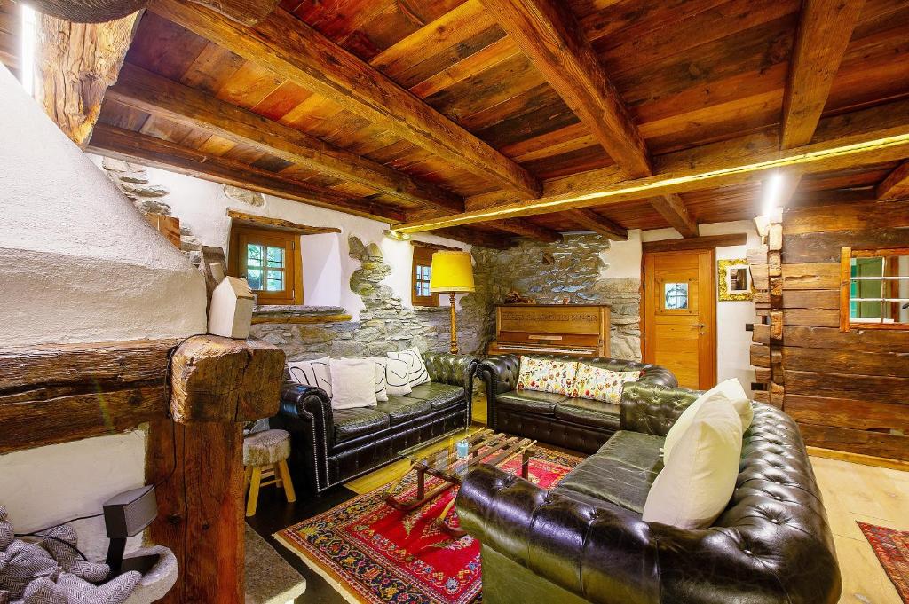 a living room with leather furniture and a stone wall at Le Chalet du Coq Rouge in Valtournenche