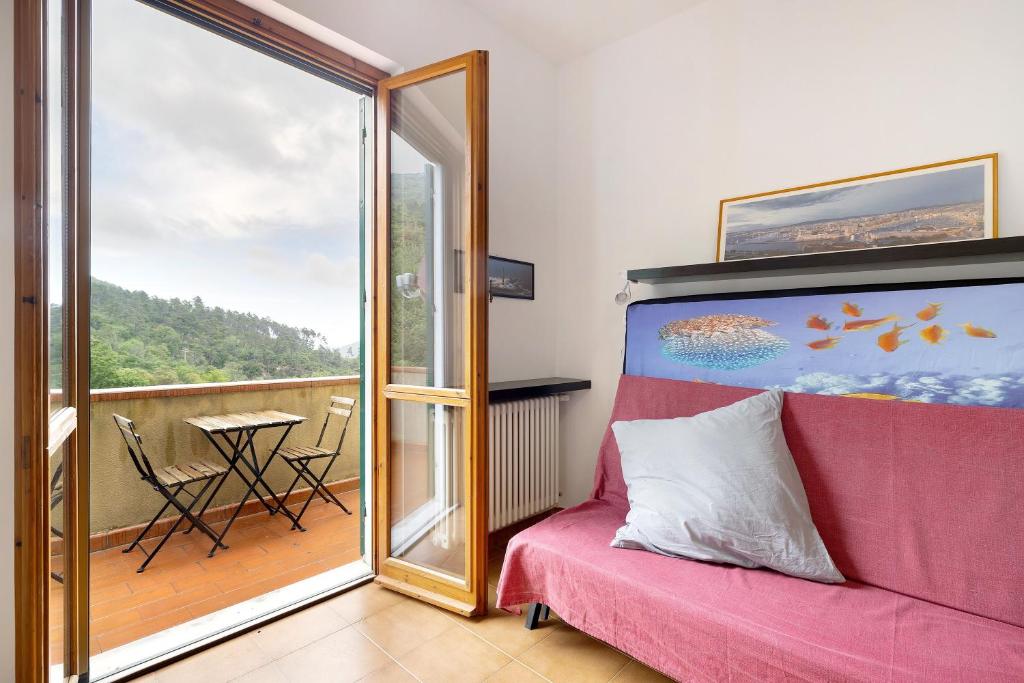 a room with a red couch and a balcony with a table at Elena e Joerg 2 in Vezzi Portio