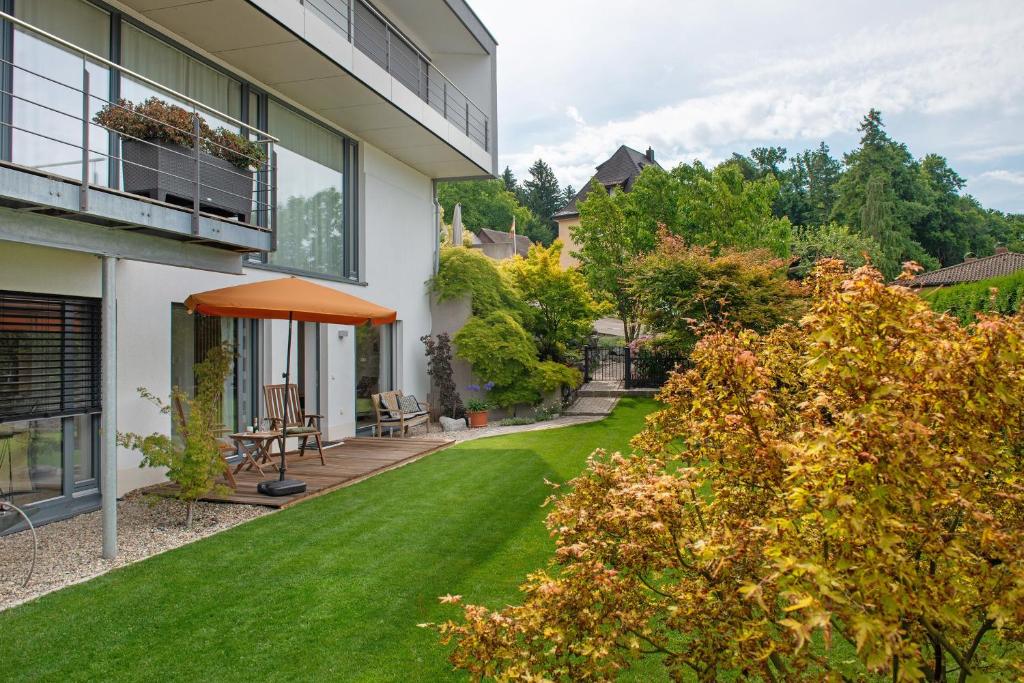 a yard with green grass and an orange umbrella at Meili's Haus in Uhldingen-Mühlhofen