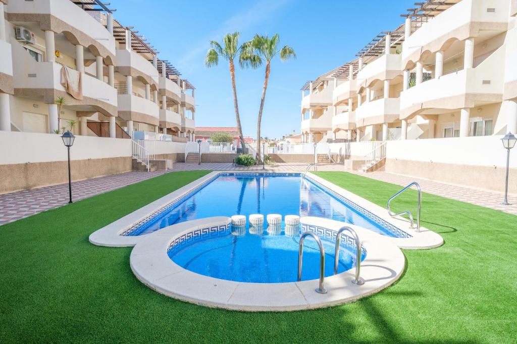 a swimming pool in the middle of a lawn in front of a building at Playasol in Vinarós
