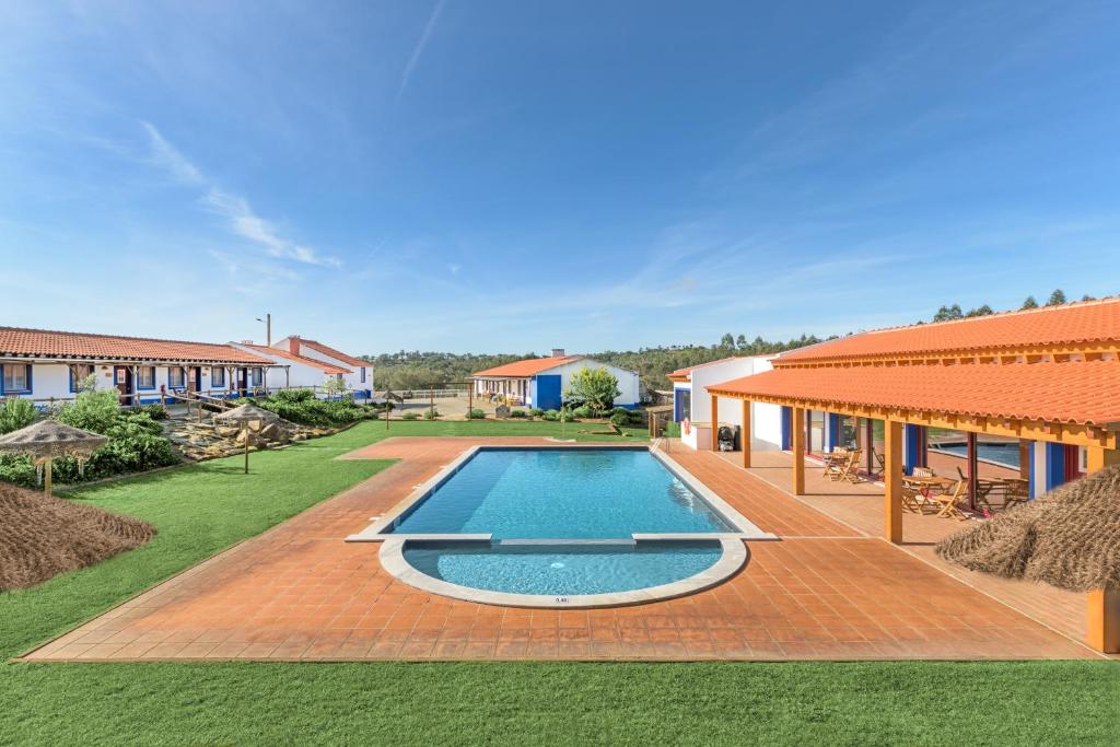 a swimming pool in a yard next to a house at Herdade Vale de Gaios in Odemira