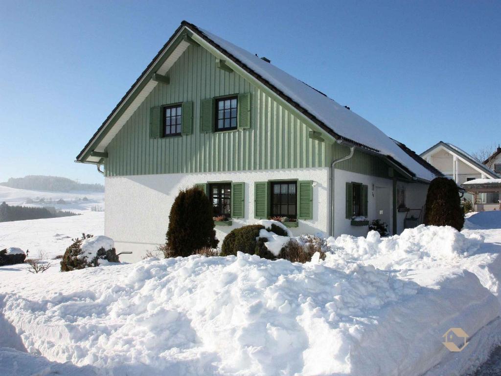 a green and white house in the snow at Ferienwohnung Ketterer in Breitnau