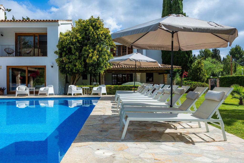 a row of chairs and an umbrella next to a pool at Can Toni in Pollença