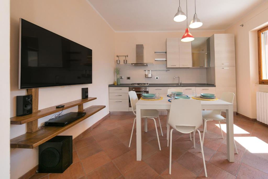 a kitchen with a white table with chairs and a flat screen tv at Al posto giusto - appartamento Sole in Riotorto