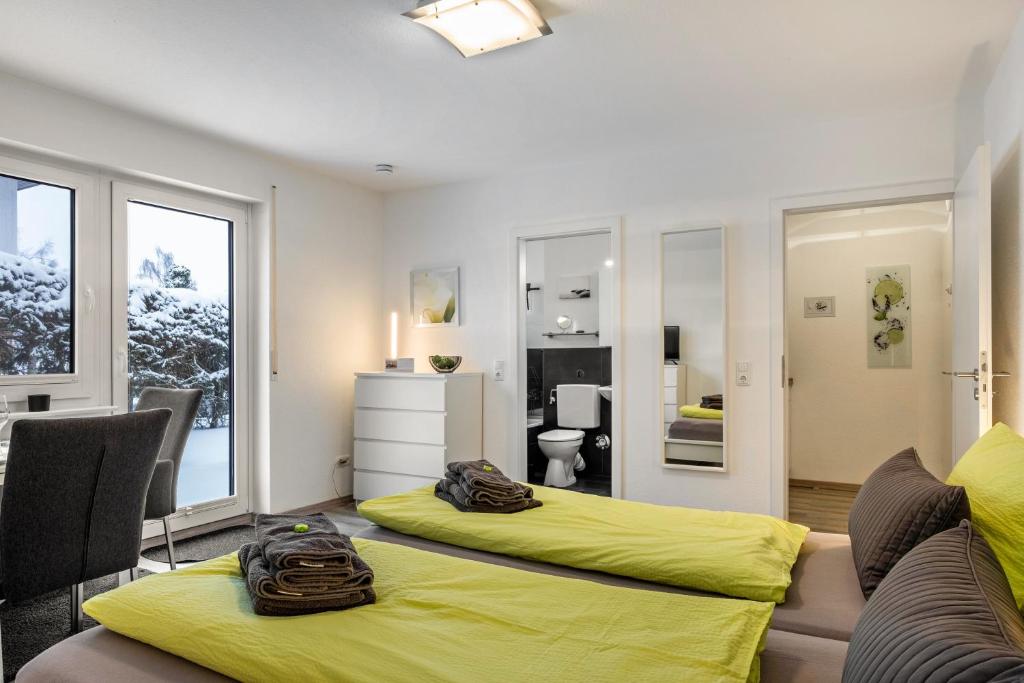 a bedroom with two beds with yellow sheets at Schwarzwaldblick K App 4 mit Pool in Schönwald