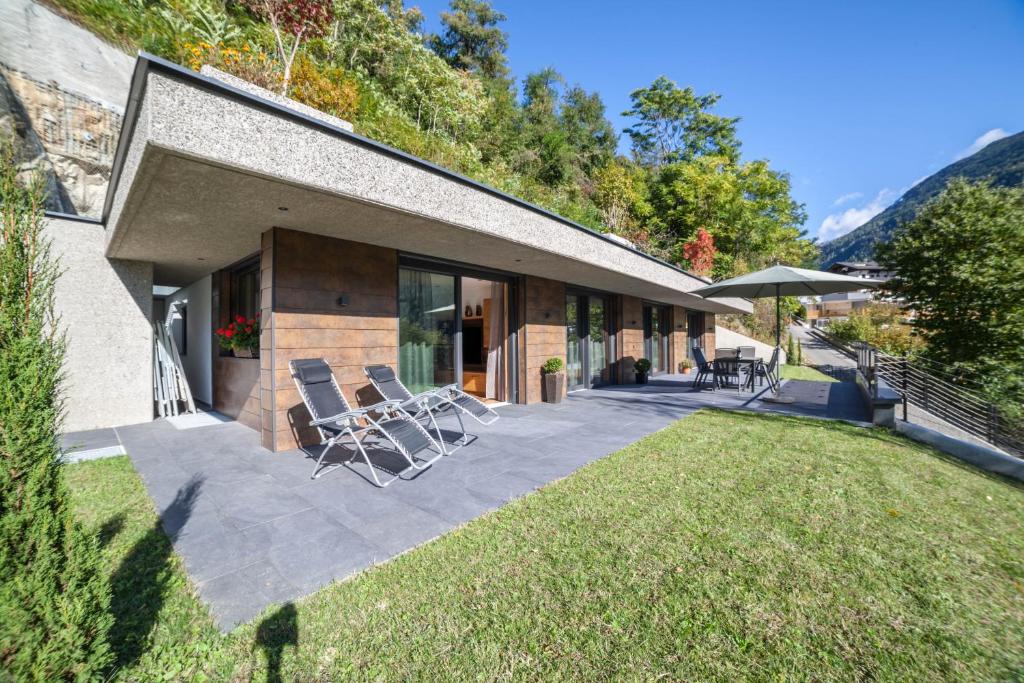 a house with chairs on a patio with a yard at Chalet Riad in Saltusio