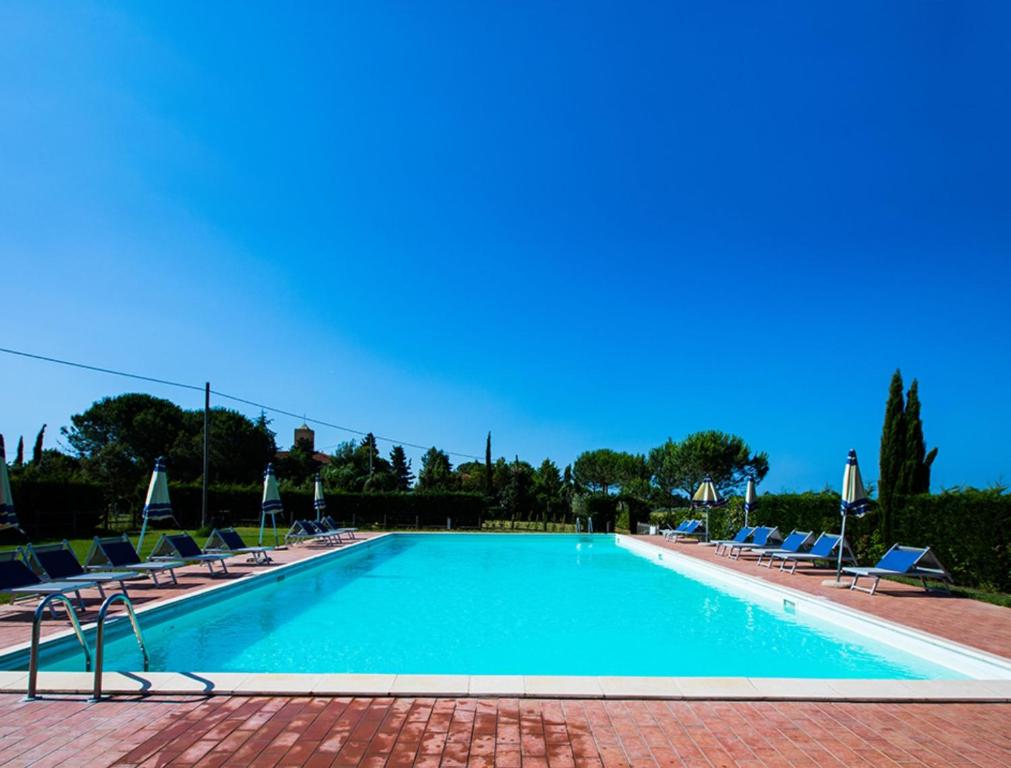 a large swimming pool with lounge chairs and blue skies at Podere Simonetta - A1 in Cecina