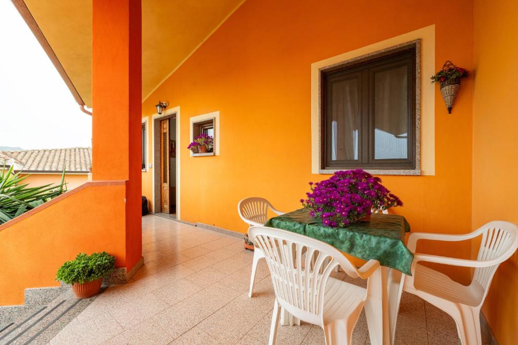 a table and chairs on a porch with an orange wall at Gaia Casa Vacanze in San Giovanni Suergiu