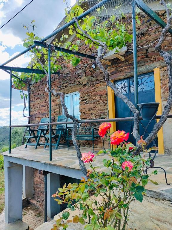 a stone house with a wooden deck and flowers at Casa de Canelas - Refugio Terroir in Açoreira