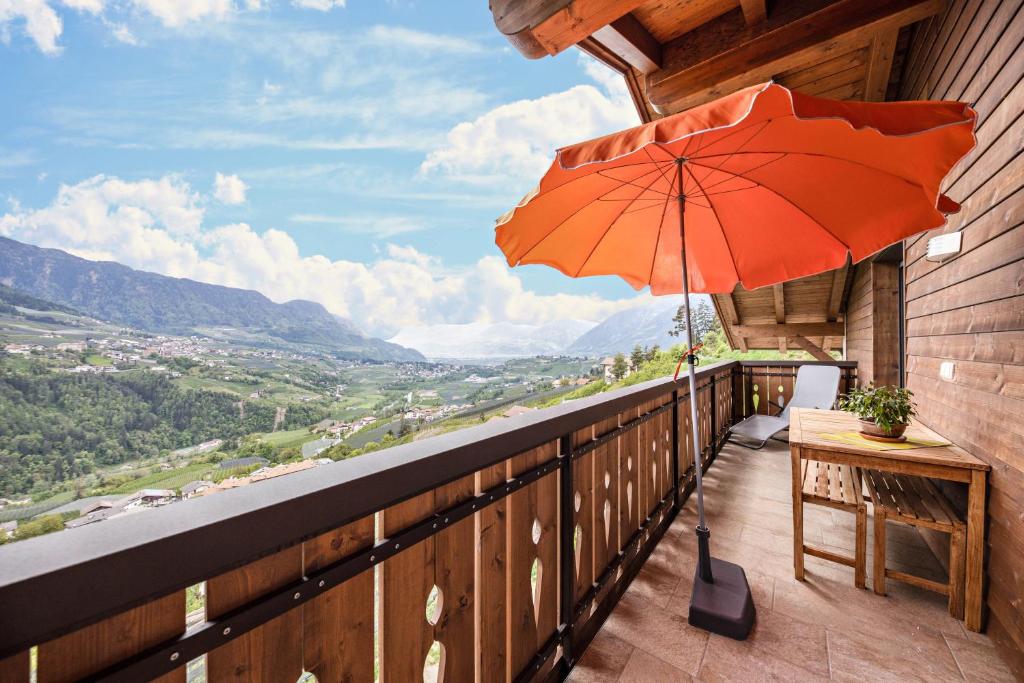a balcony with an orange umbrella and a table at Panoramawohnung Annaheim in Rifiano