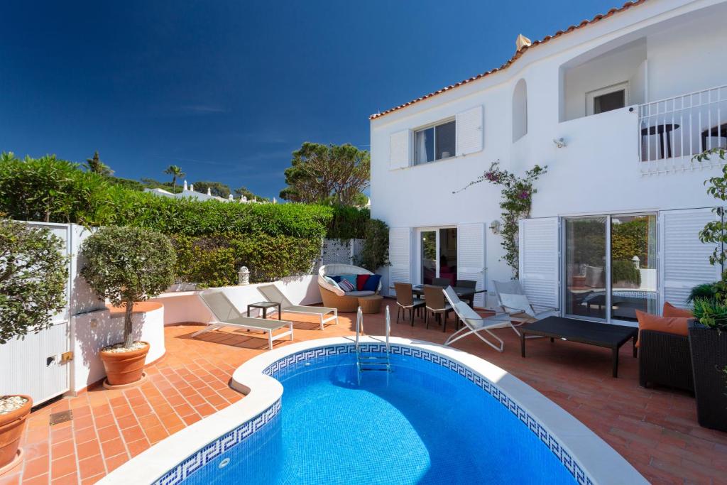 a villa with a swimming pool in front of a house at Vila Senna in Vale do Lobo