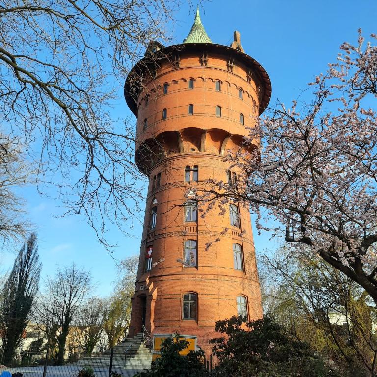 ein hoher Backsteinturm mit spitzem Dach in der Unterkunft Café Wasserturm Cuxhaven in Cuxhaven