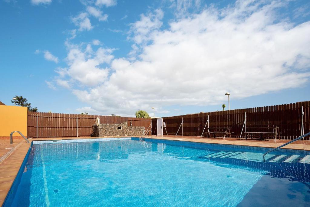 a large blue swimming pool next to a fence at Villa Dayely in Corralejo