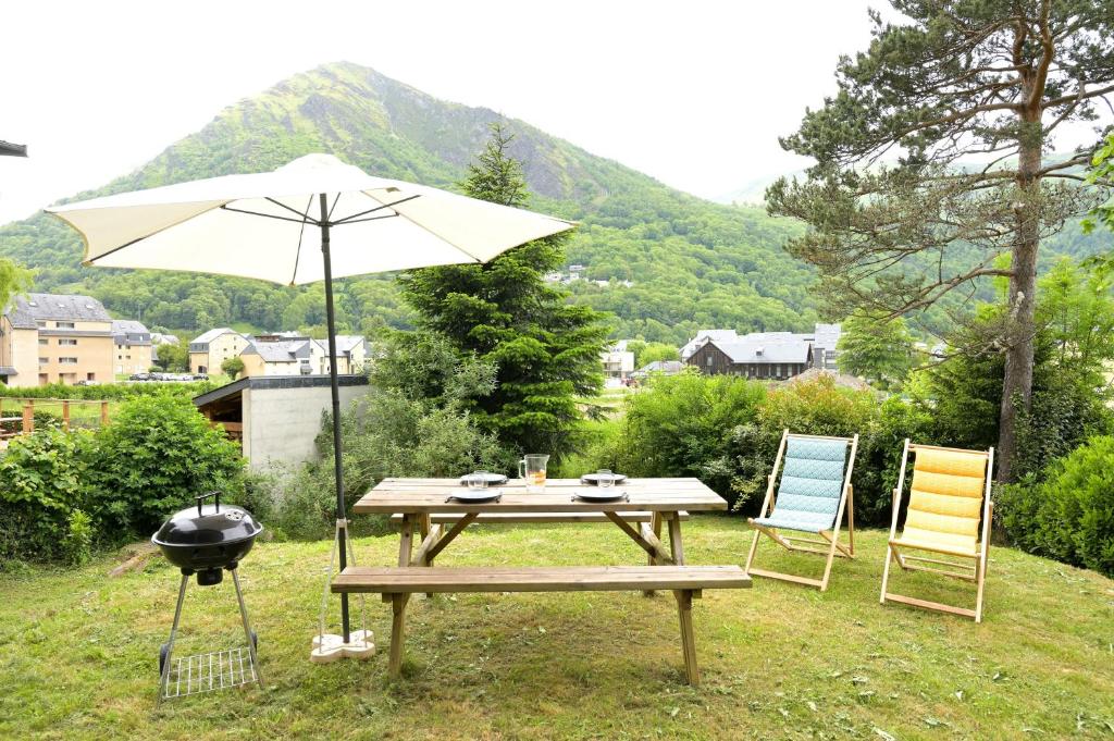 a picnic table with an umbrella and a grill at Chalet Appartement Les Isards in Saint-Lary-Soulan