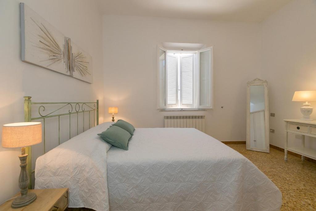 a bedroom with a white bed with a green pillow at Brezza Marina Apartment in San Vincenzo