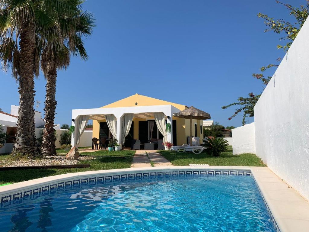a villa with a swimming pool in front of a house at Chalet con piscina en Menorca in Cala en Bosc