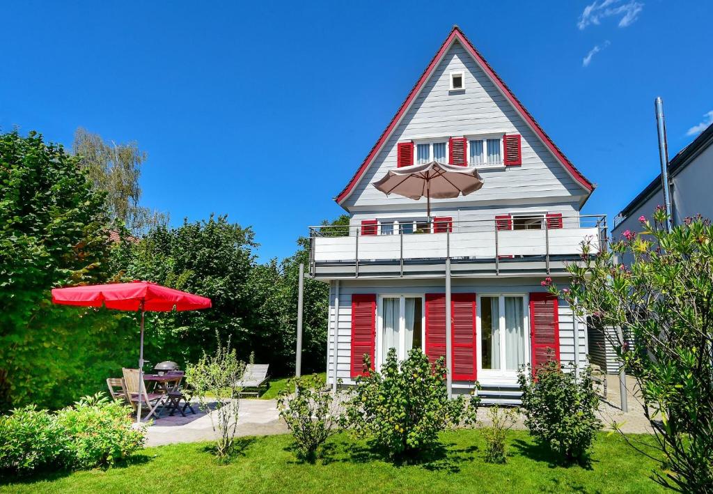 a red and white house with an umbrella and a table at Villa Kunterbunt in Lindau