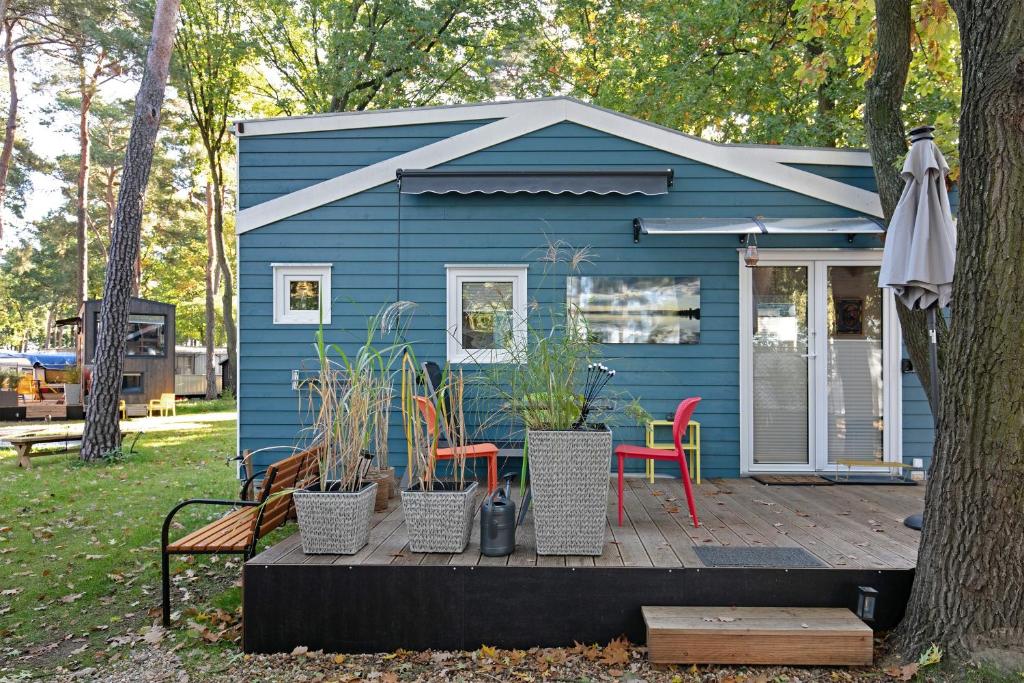 a blue house with a table and chairs on a deck at Tiny House Nr 1 in Schwielowsee