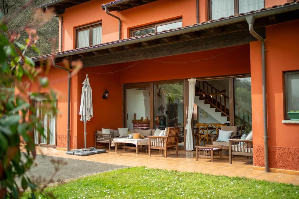 an orange house with a patio with chairs and an umbrella at Casa Carmen in La Vega