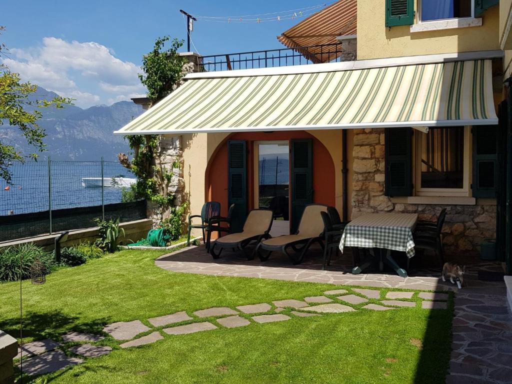 a house with a table and chairs on a lawn at Apartment CASA SPIAGGIA by Interhome in Castelletto di Brenzone
