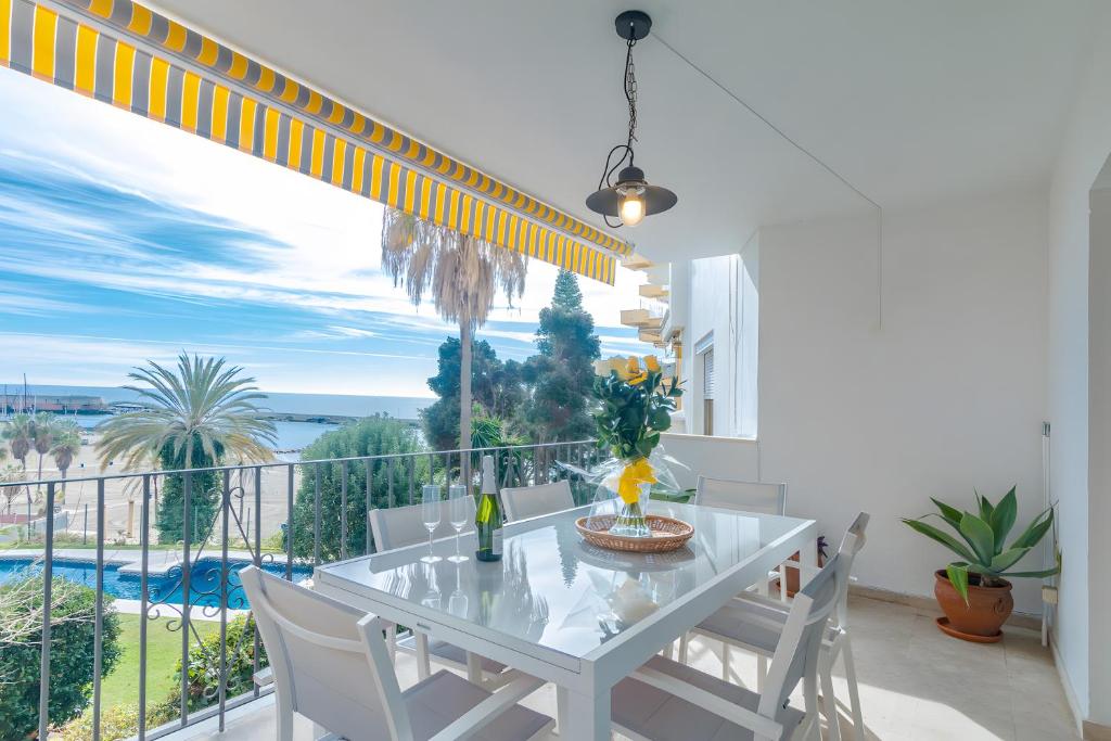 a white dining room with a table and a balcony at Large Apartment Marbella del Mar in Marbella