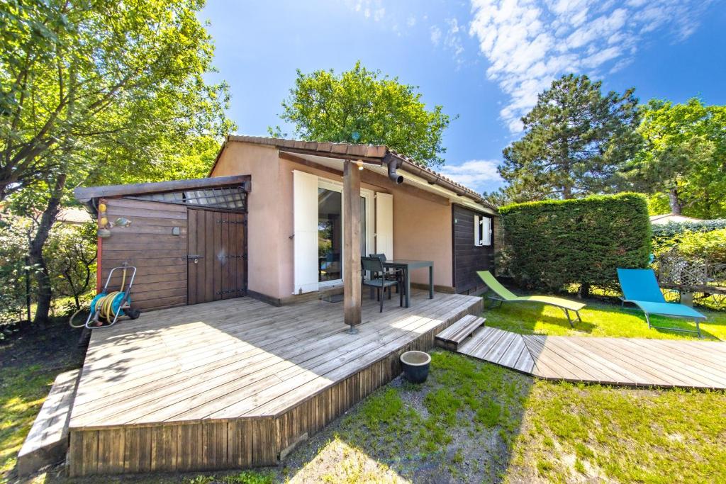 a tiny house with a deck in the yard at Chalet dans résidence piétonne in Hourtin