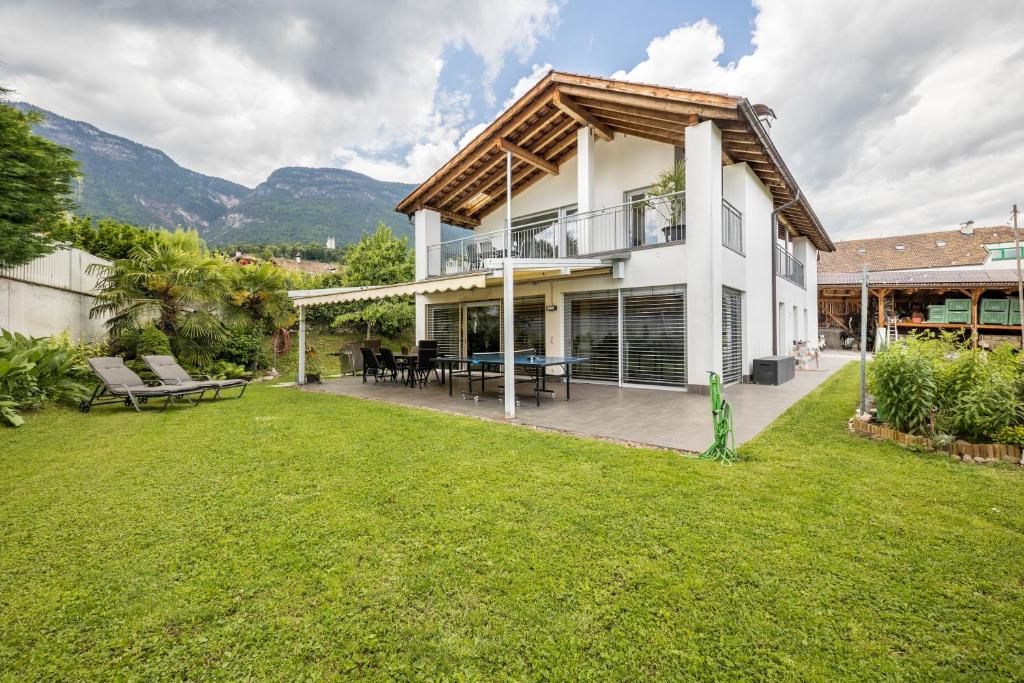 a white house with a patio and a yard at Angerblick Apartment in Appiano sulla Strada del Vino