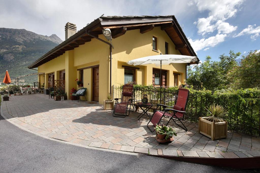 a house with a patio with chairs and an umbrella at La casa di Alice in Gignod