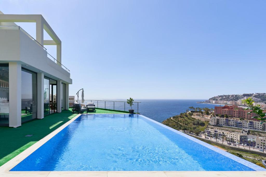 a swimming pool on the side of a house overlooking the ocean at Villa Joya del Mediterraneo in Almuñécar