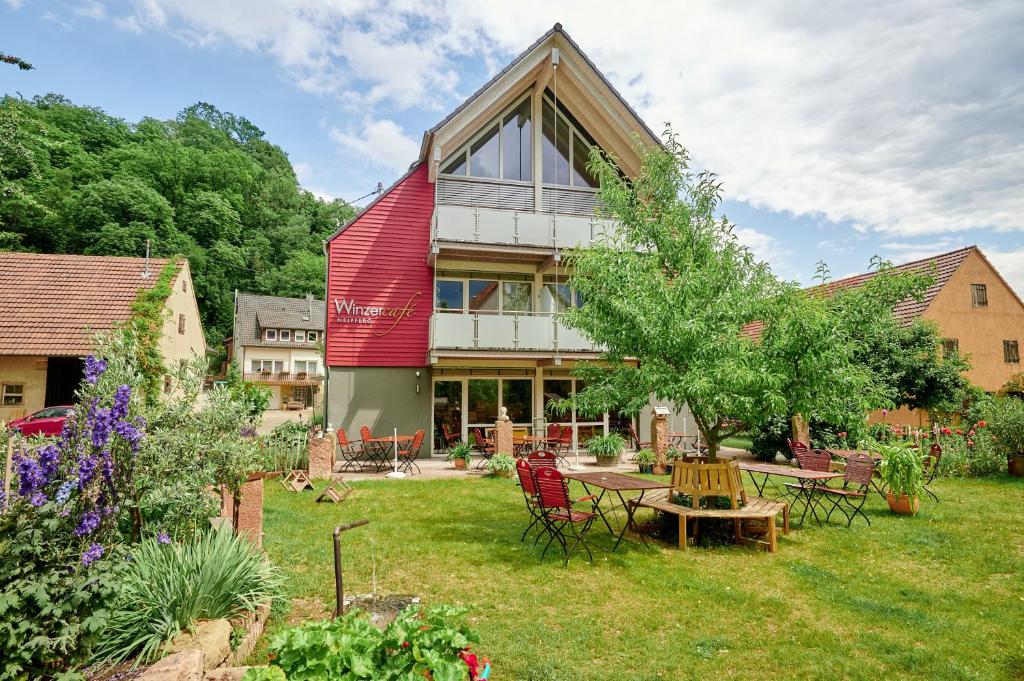 a house with a red roof with a table in the yard at Winzercafé Neipperg in Brackenheim