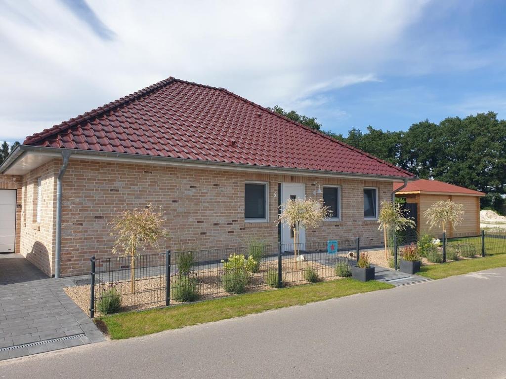 a brick house with a red roof on a street at Haus Seestern in Walchum