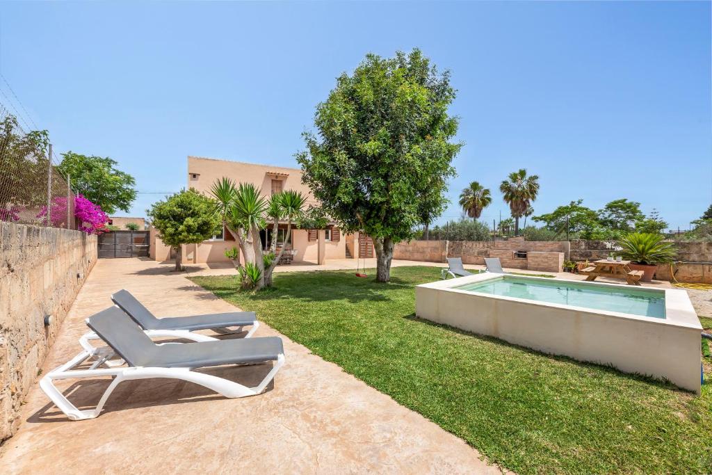 a yard with lounge chairs and a swimming pool at Es Cos in Algaida