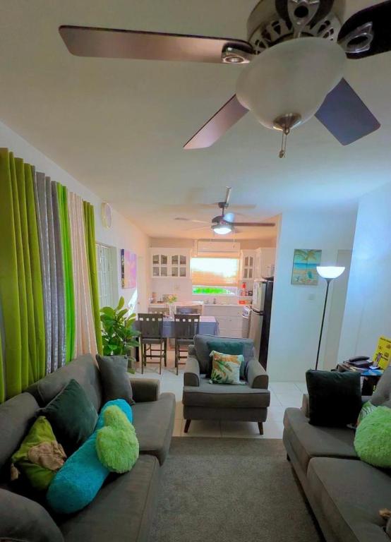 a living room with two couches and a ceiling fan at Cool Stay in Christ Church