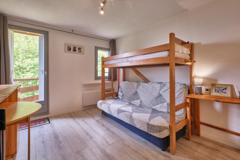 a bedroom with a bunk bed and a desk at Prapoutel pied des pistes in Les Adrets