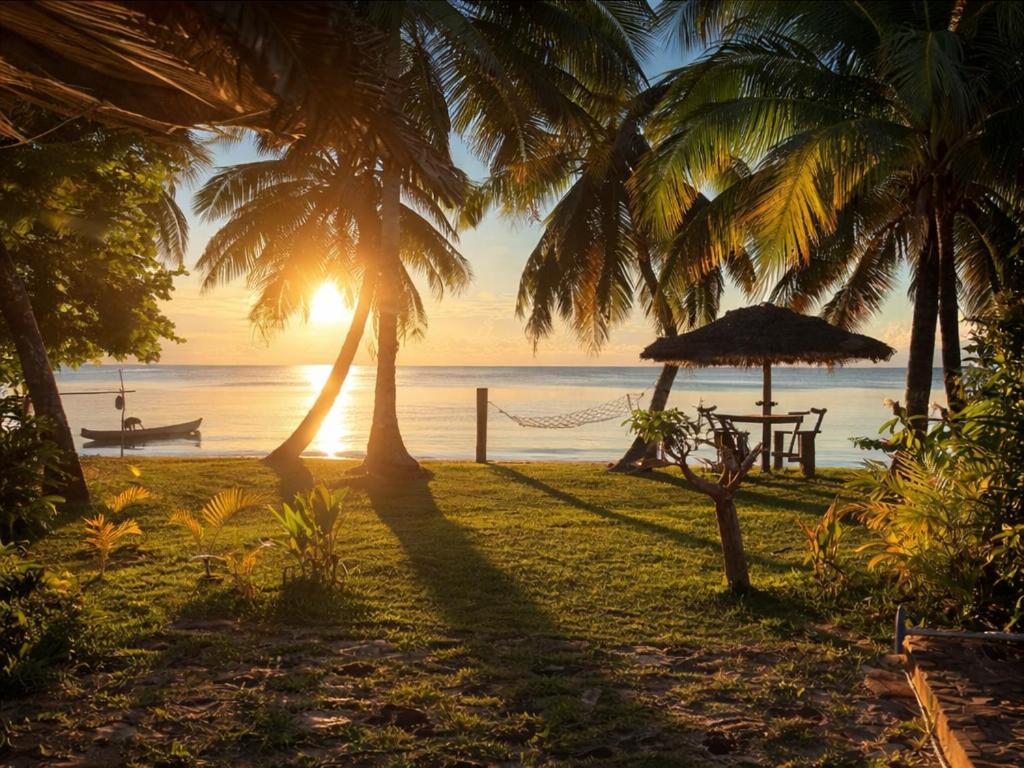 a beach with a table and an umbrella and the ocean at Chez L'Avocatier in Sainte Marie