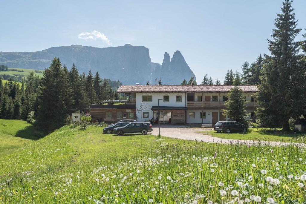 a building with cars parked in a field of flowers at Sabina Dolomites Santner in Alpe di Siusi