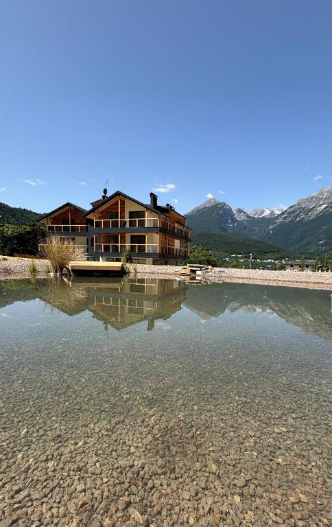 a house sitting on top of a body of water at Arnica Alpin Lodge in Cavedago