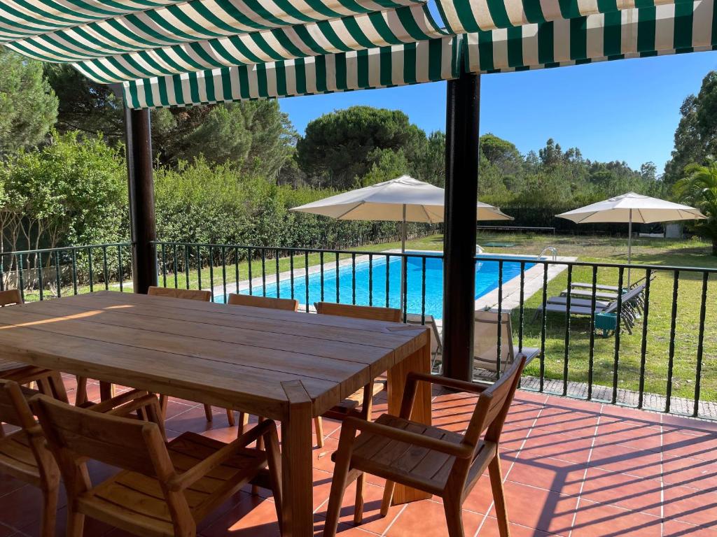 a wooden table and chairs on a patio with a pool at Casa dos Pinheiros in Giz