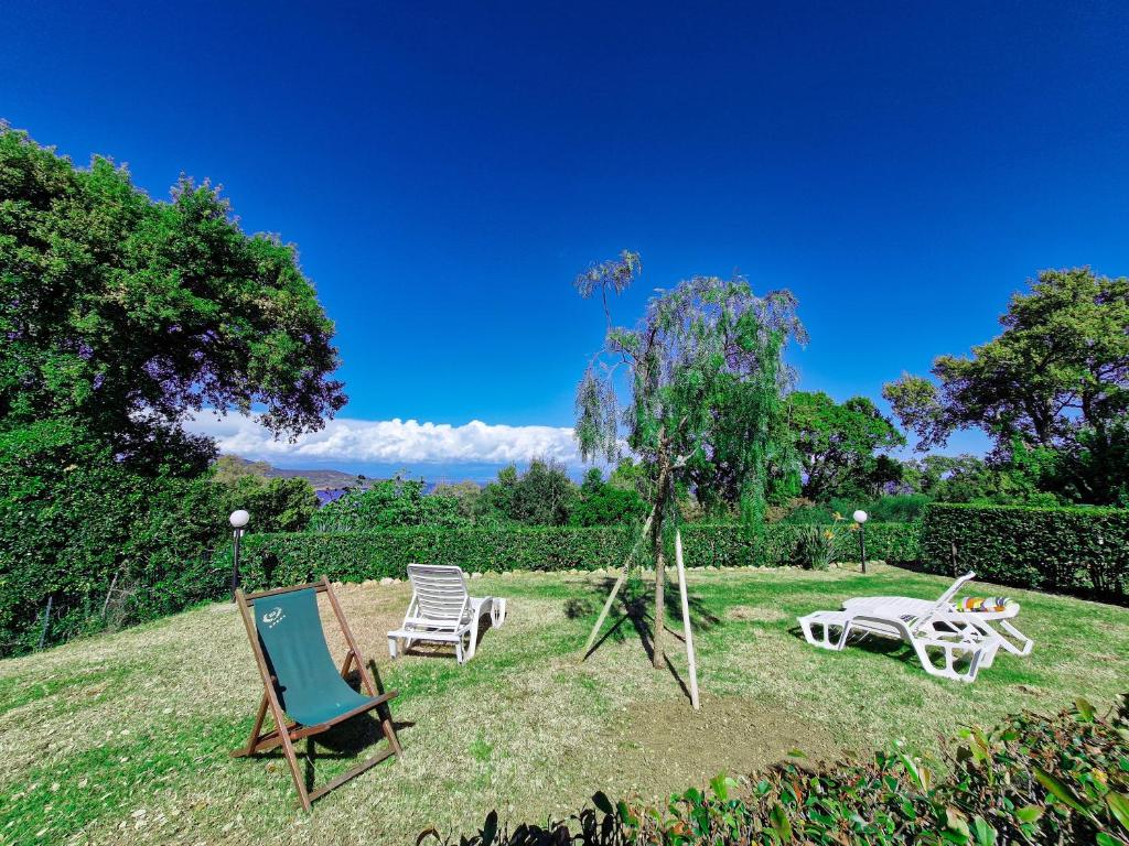 two chairs and a table and chairs on the grass at Appartamenti Le Querce App. Melograno in Capoliveri